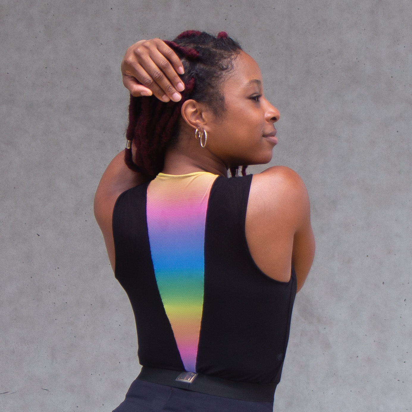 A photo of a black woman wearing a black and rainbow croptop