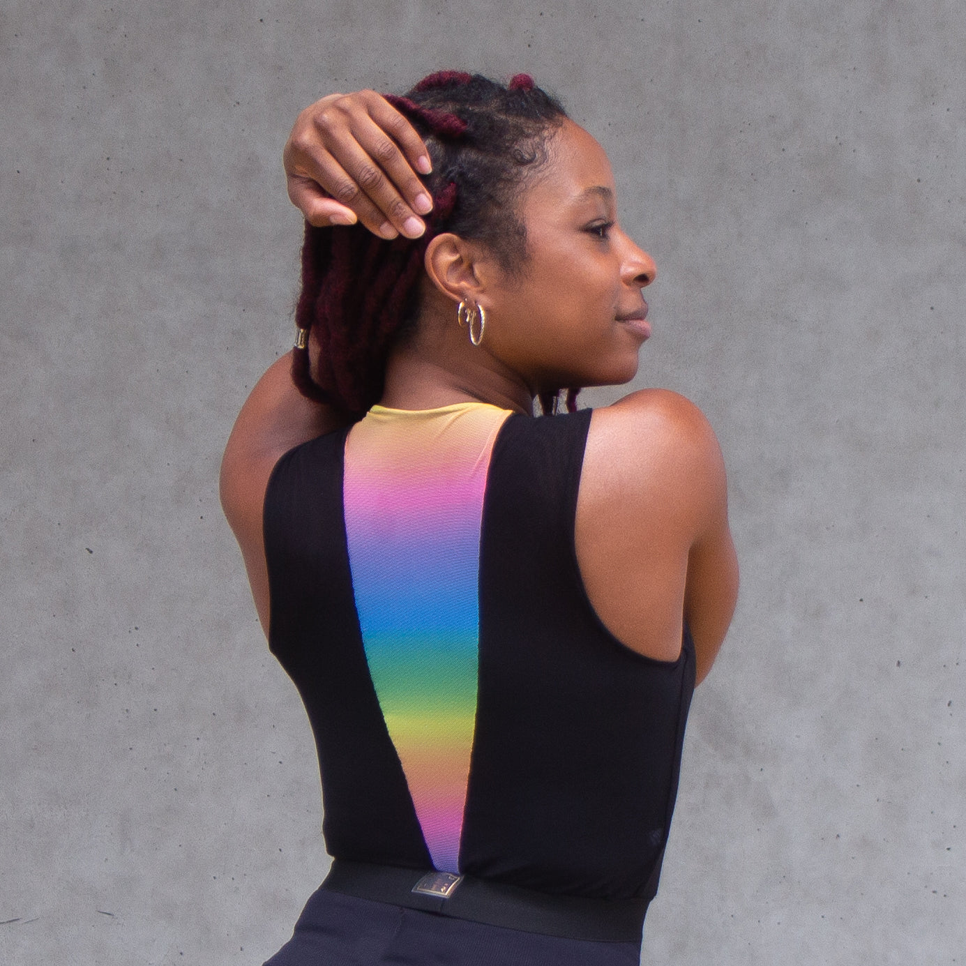 A photo of a black woman wearing a black and rainbow croptop 