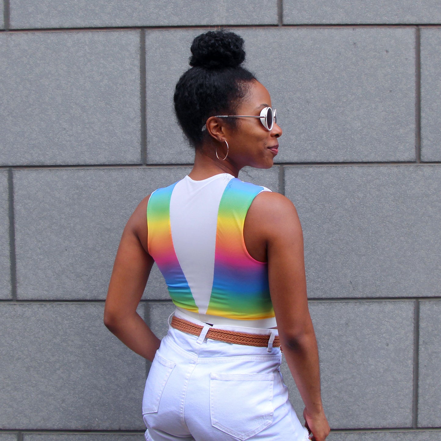 A woman wearing an Athtelier rainbow and white mesh croptop