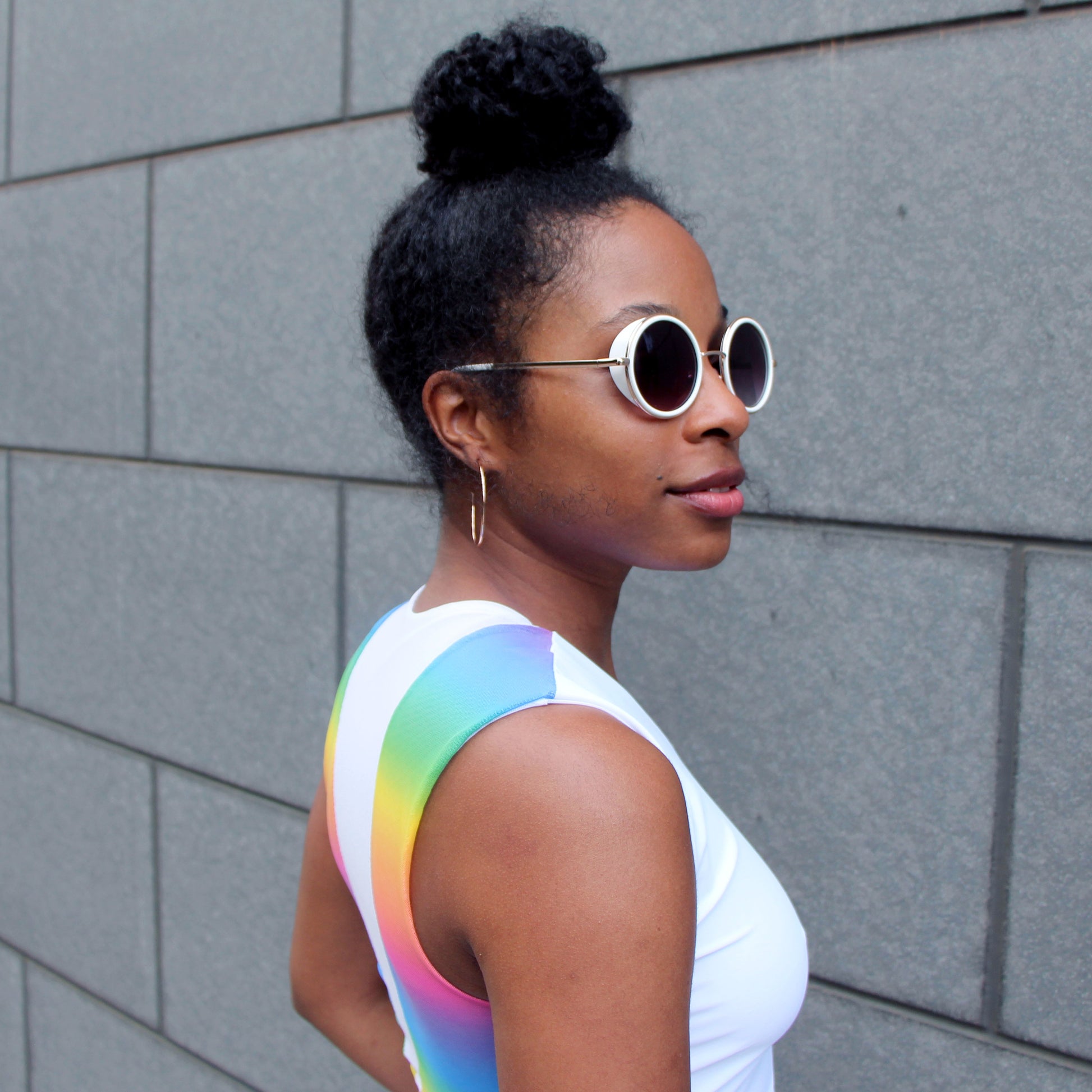 A 3/4 closeup of a woman wearing a white and rainbow top