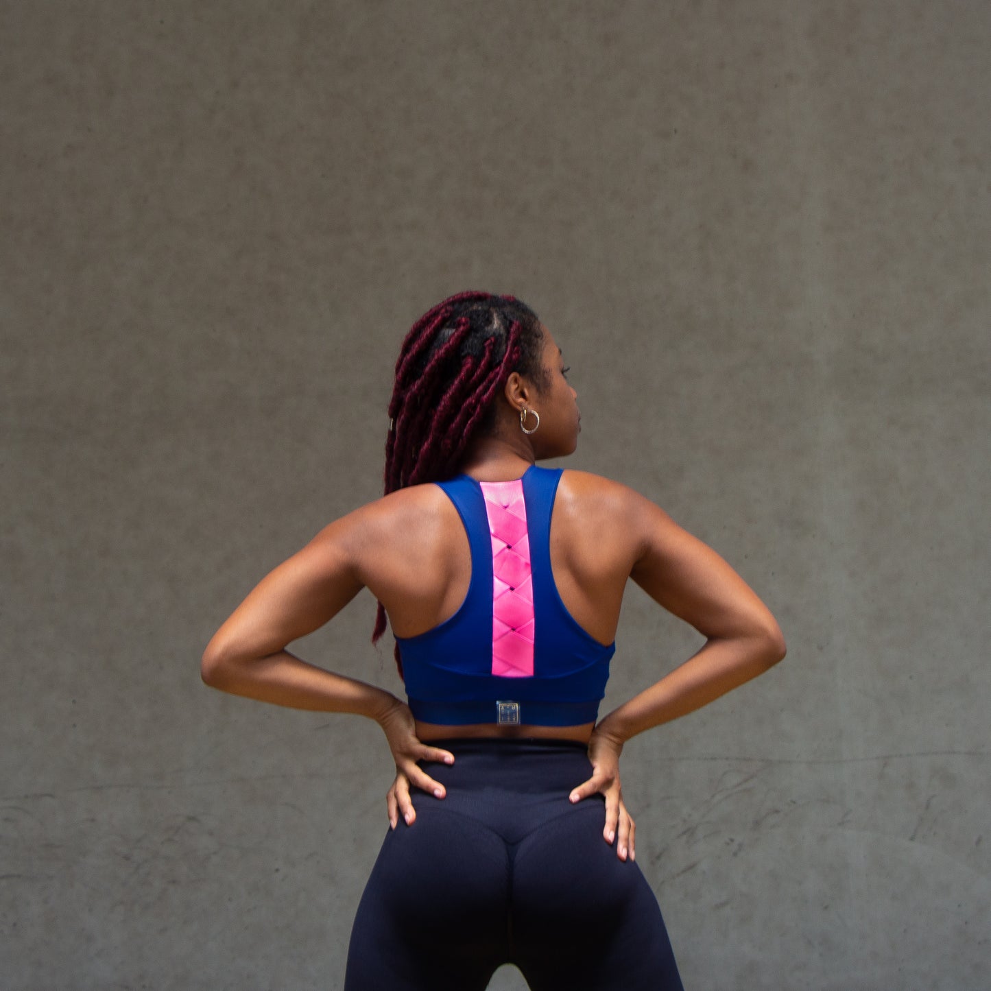 a photo of a black woman's back wearing a navy and magenta sports bra