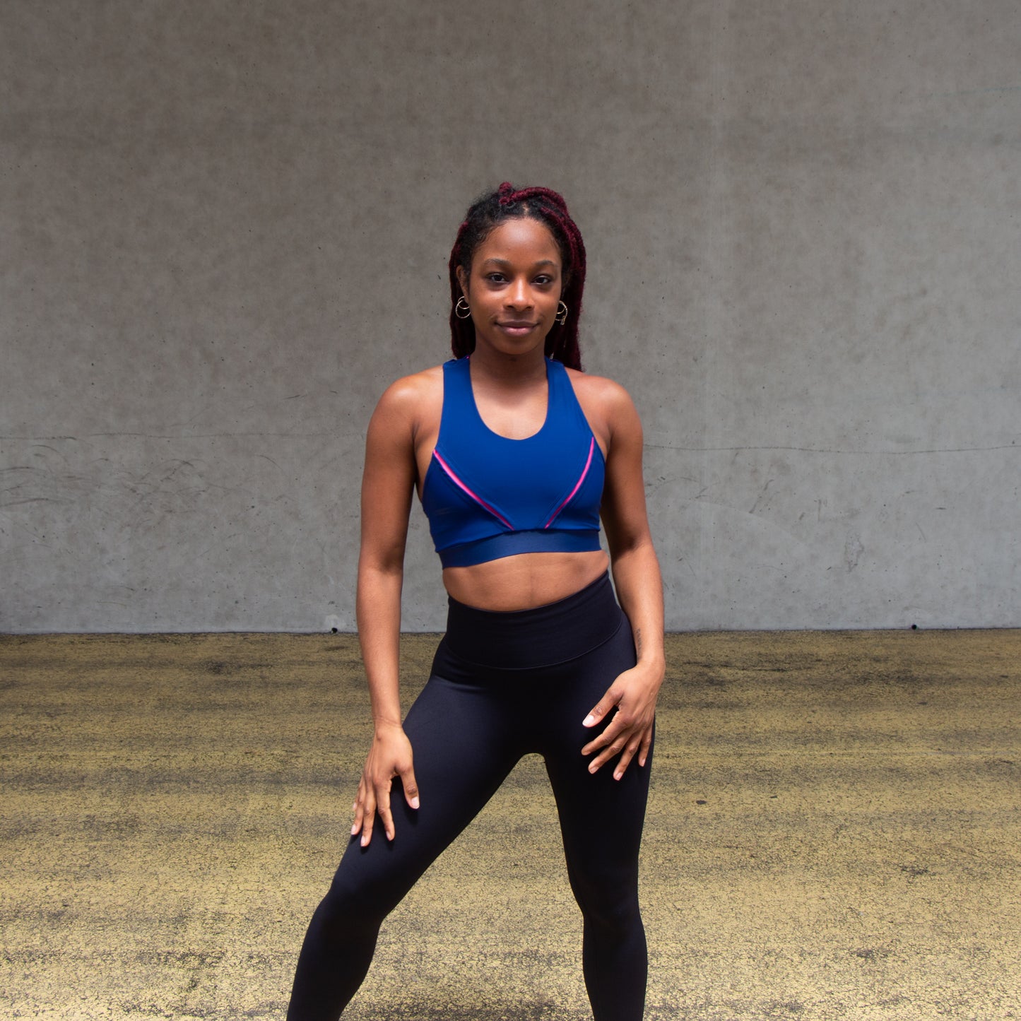 a photo of a black lady wearing a royal blue and pink sports bra