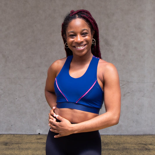 a photo of a black woman smiling and wearing a navy and pink sports bra
