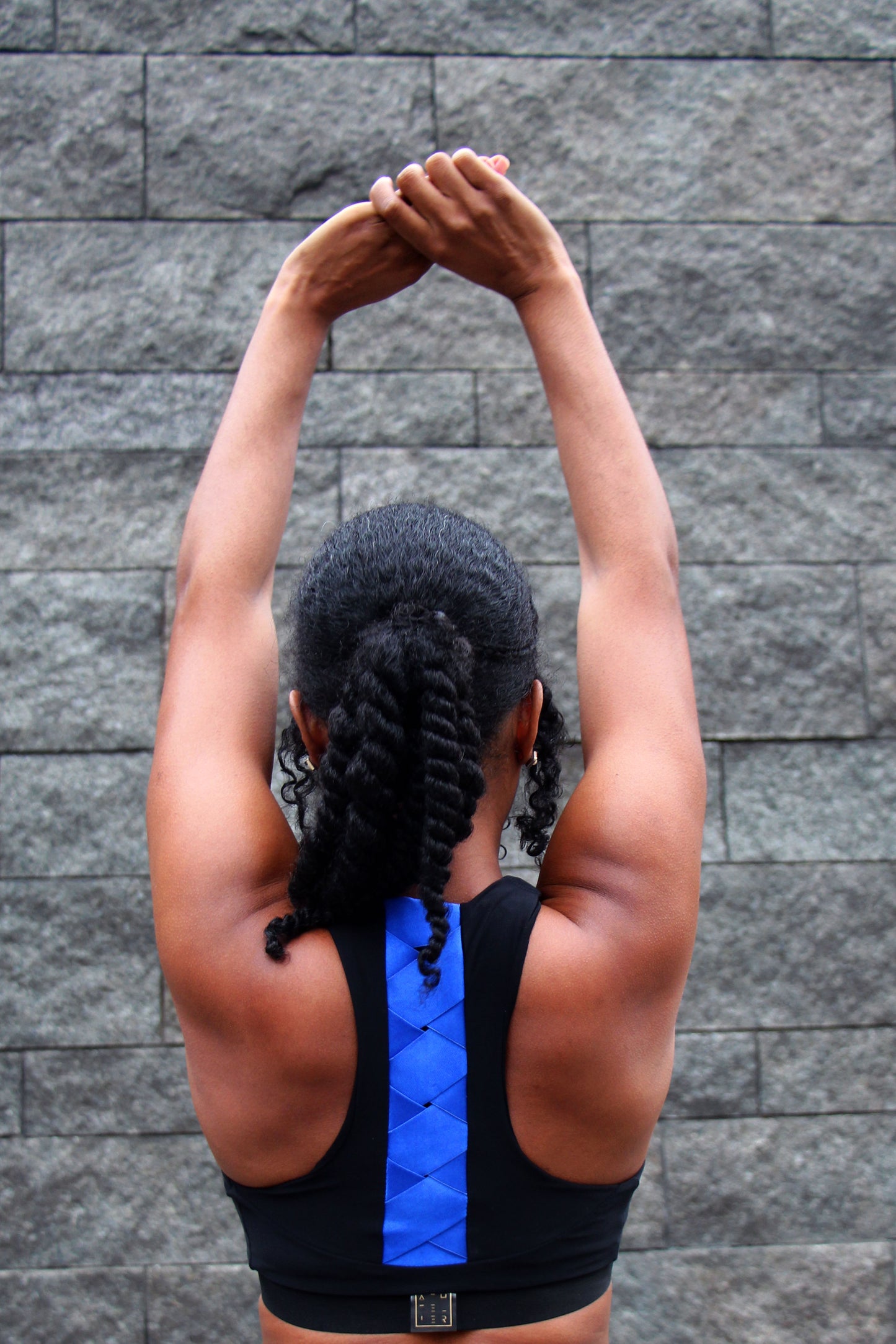 The back view of a woman wearing a black and blue sports bra