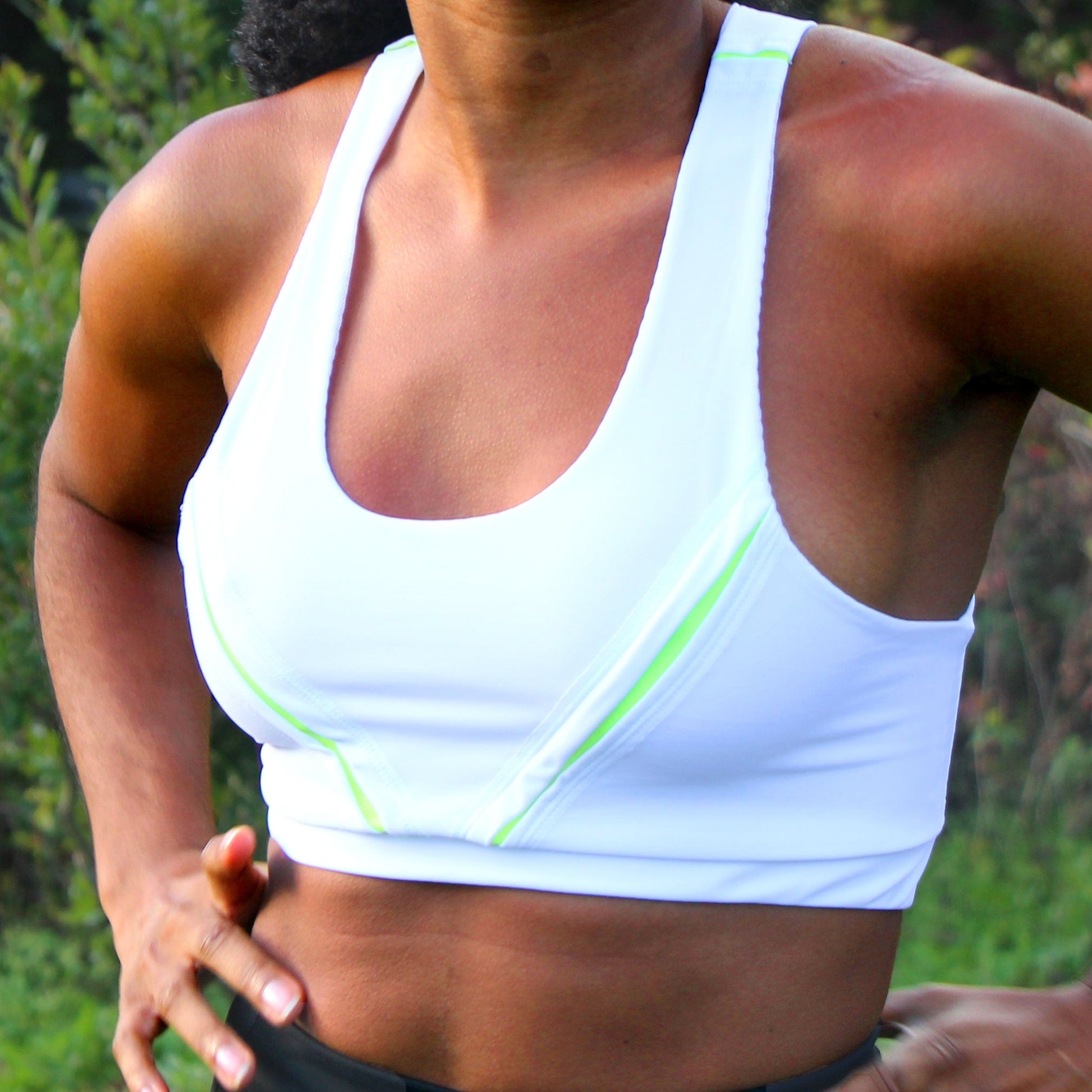 A closeup of a woman wearing a white and neon yellow sports bra